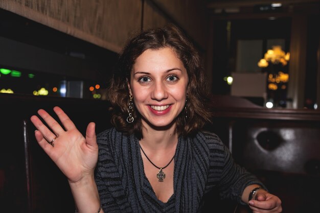 Retrato casual de mujer joven emocional positiva en club de restaurante nocturno en la mesa. Concepto de estilo de vida de la ciudad de noche. Copia espacio