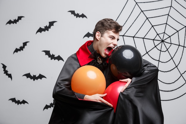 Foto retrato del caucásico hermoso en traje de halloween del vampiro con el globo colorido.