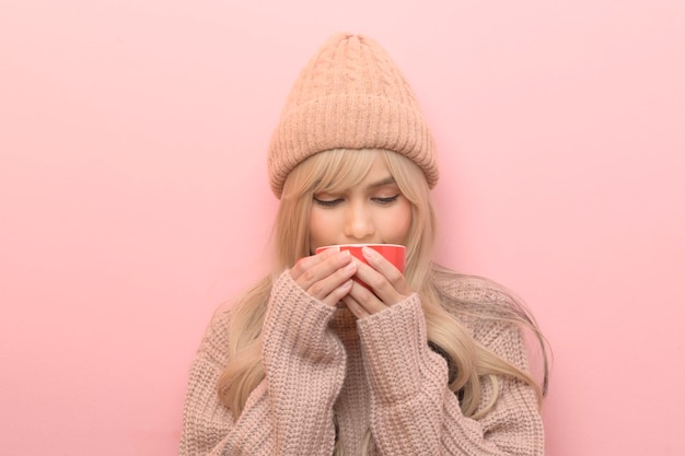 retrato, de, caucásico, mujer joven, llevando, suéter, bebida, café, encima, fondo rosa