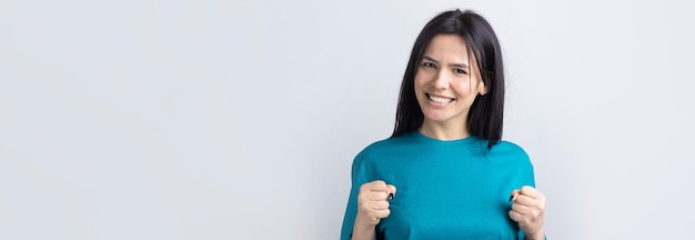 Retrato de cerca de gritos atractivos en ganar sonriendo con puños levantados joven ella su chica con ropa de camisa de jeans aislado sobre fondo gris