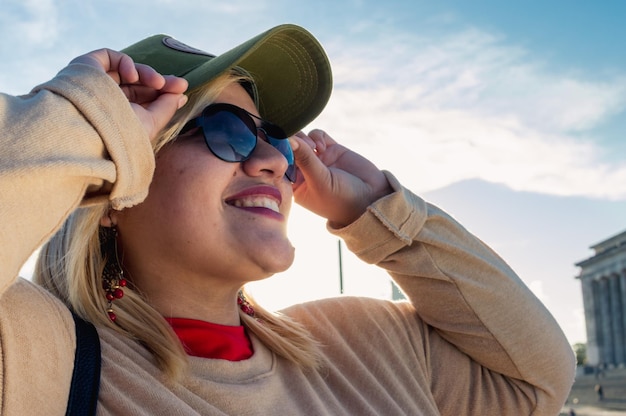 Retrato de cerca de una joven turista latina al aire libre sonriendo mirando hacia un lado