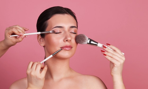 Retrato cercano del rostro de una mujer con pinceles para maquillaje