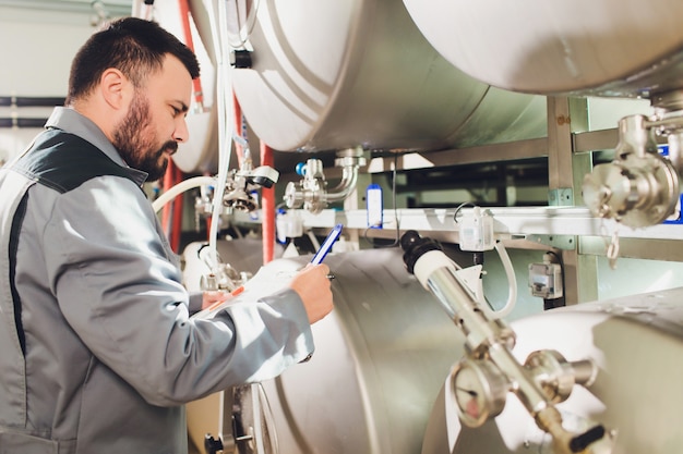 Retrato de cervecero que está haciendo cerveza en su lugar de trabajo en la cervecería.