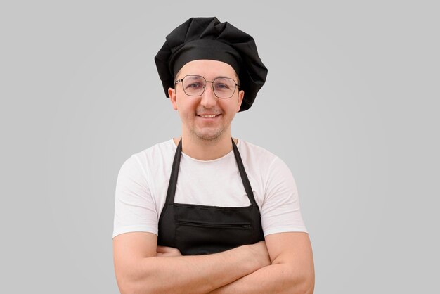 Retrato de un chef con los brazos cruzados mirando a la cámara sobre un fondo gris