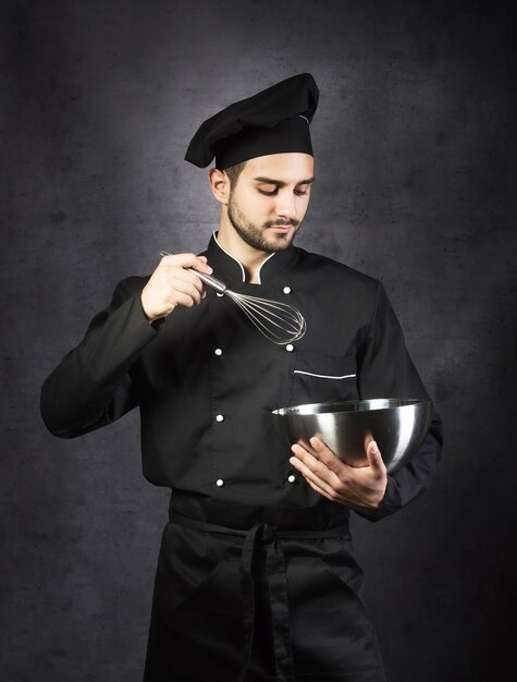 Retrato de un chef de cocina con fondo gris uniforme negro