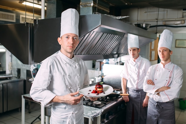 Retrato del chef en la cocina del restaurante con un plato de foie gras.