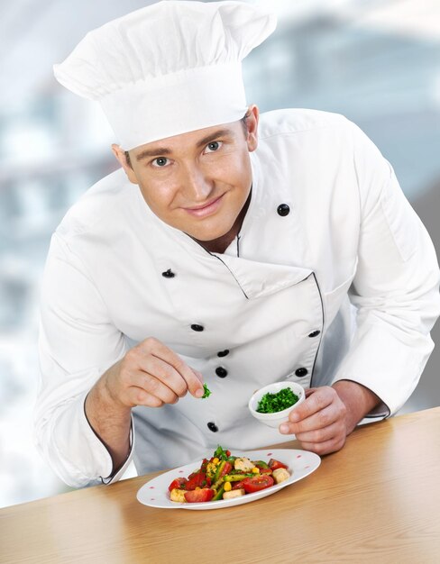 Retrato de un chef masculino que prepara una ensalada aislada en el fondo