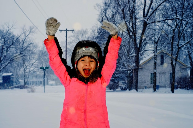 Retrato de una chica alegre de pie en el campo durante la nevada