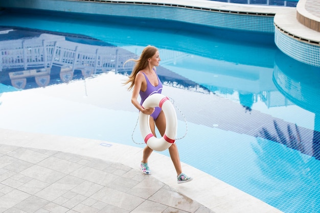 Retrato de una chica atractiva con el pelo largo de pie cerca de la piscina