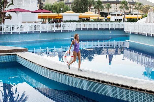 Retrato de una chica atractiva con el pelo largo de pie cerca de la piscina