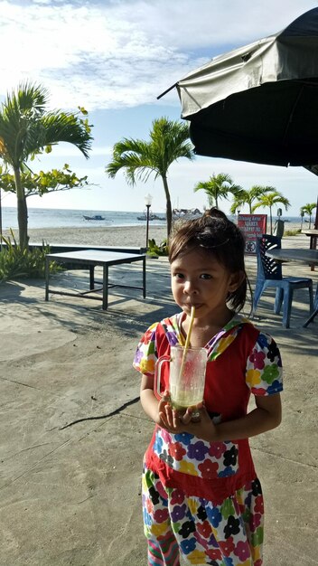 Retrato de una chica bebiendo en la playa