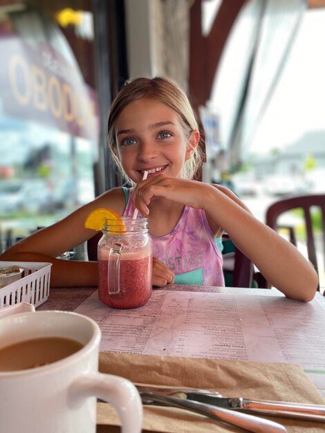 Foto retrato de una chica bebiendo un vaso en la mesa