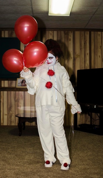 Foto retrato de una chica disfrazada sosteniendo globos rojos