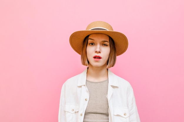 retrato de una chica divertida en un fondo rosa mira a la cámara con una cara graciosa sorprendida