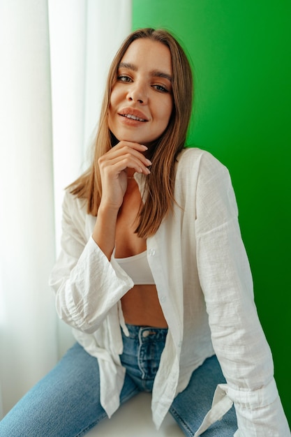 Retrato de una chica encantadora y atractiva con camiseta corta y camiseta posando sobre un fondo verde de estudio