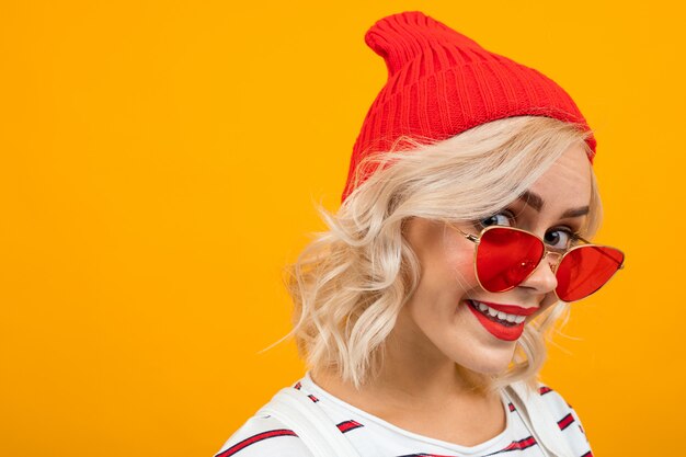 Retrato de una chica encantadora muy linda con el pelo blanco en un sombrero rojo sobre amarillo