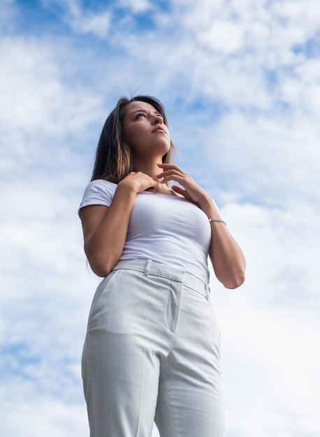 Retrato de una chica de estilo casual mirando el cielo azul al aire libre soñando