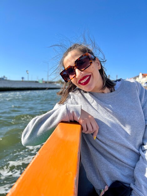 retrato de una chica feliz con gafas de sol tomando un paseo en bote por el río