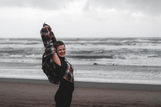 Foto retrato de una chica fuerte, independiente, despreocupada y feliz con el telón de fondo del mar en otoño