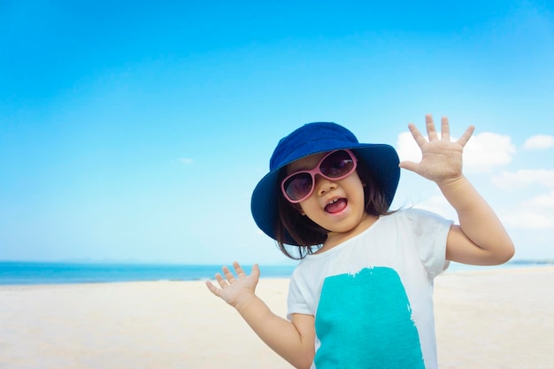 Retrato de una chica con gafas de sol de pie en la playa contra el cielo