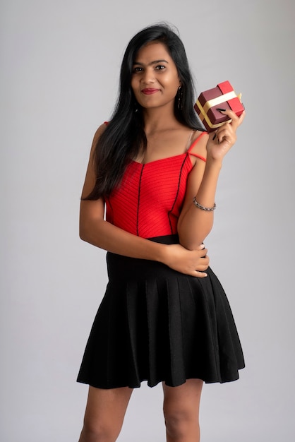 Retrato de una chica guapa sosteniendo y posando con una caja de regalo.