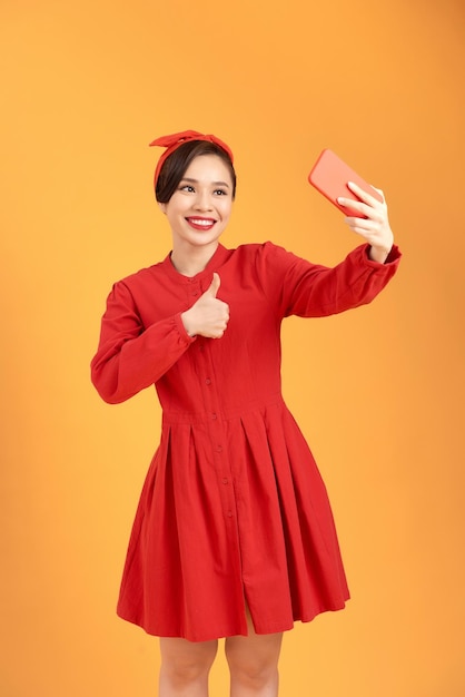 Retrato de una chica guapa tomando un selfie aislado sobre fondo amarillo