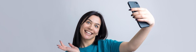 Retrato de una chica guapa tomando un selfie aislado sobre fondo gris