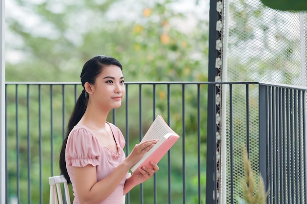 Retrato de una chica hermosa leyendo un libro en el balcón