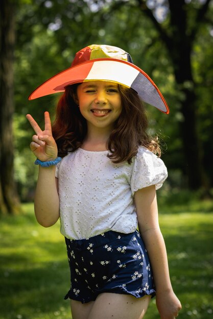 Retrato de una chica hermosa con un sombrero de bandera belga en el parque