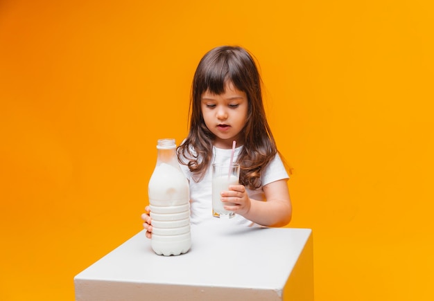 Retrato de una chica hermosa con un vaso de leche sobre fondo amarillo