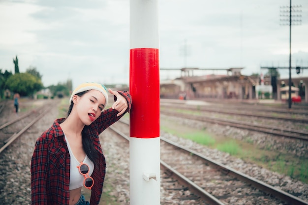 Retrato de chica hipster sentada en la mujer tailandesa de estilo vintage de ferrocarril posando para tomar una foto