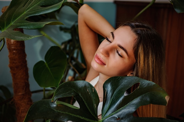 Foto retrato de una chica impresionante posando entre hojas