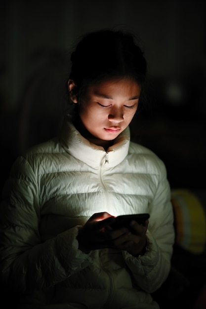 Retrato de la chica joven asiática que usa el teléfono móvil.