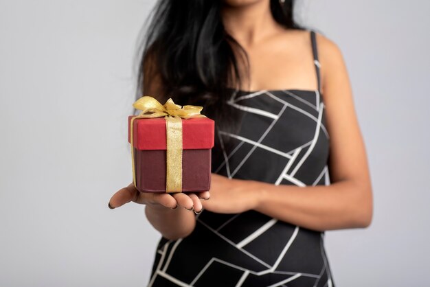 Retrato de una chica joven y bonita posando con caja de regalo