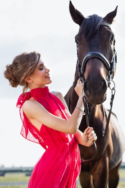 Retrato de una chica joven encantadora en un vestido con un caballo