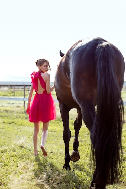 Retrato de una chica joven encantadora en un vestido con un caballo