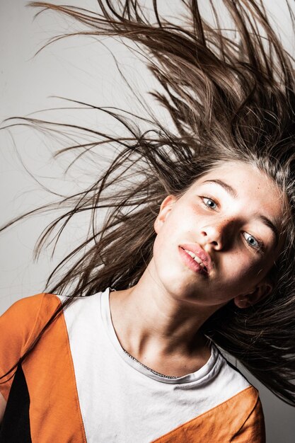 Retrato de una chica lanzando el cabello contra un fondo blanco