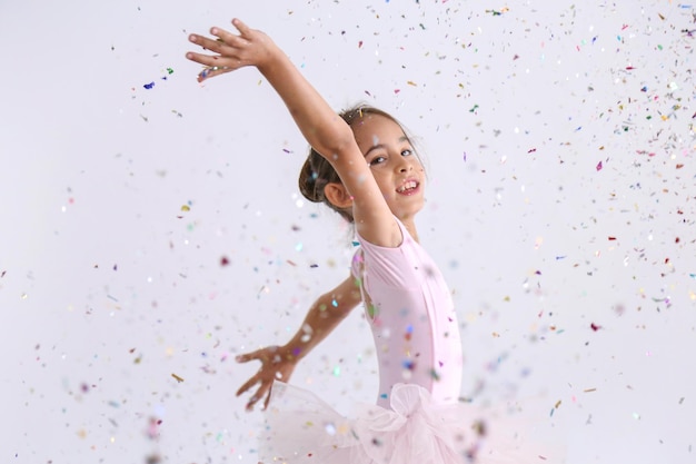 Retrato de una chica linda bailando con confeti de varios colores