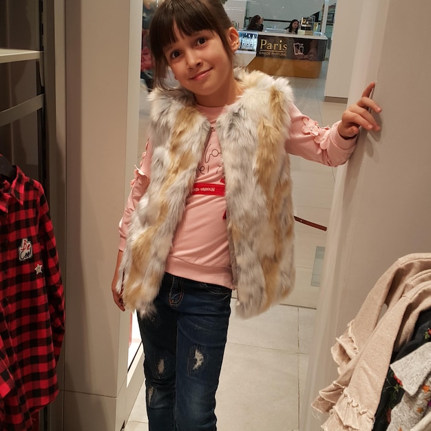 Retrato de una chica linda sonriente con una chaqueta de piel en la tienda