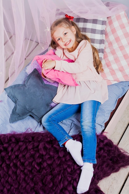 Foto retrato de una chica linda sonriente relajándose en la cama en casa