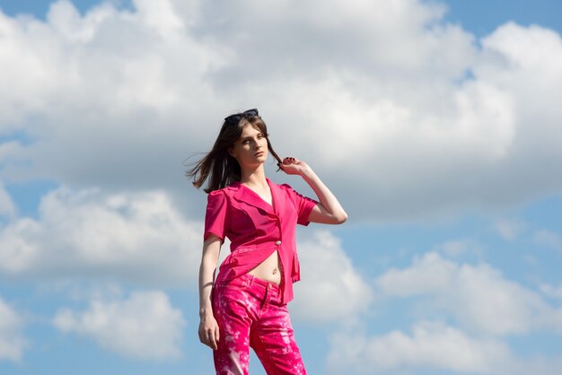 Retrato de una chica de moda con traje rosa en el cielo