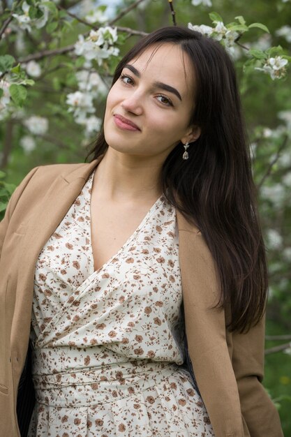 Retrato de una chica morena alegre positiva en un parque de primavera verde.