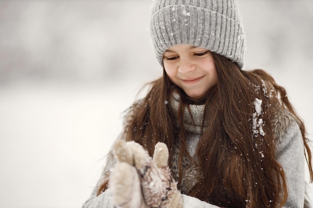 Retrato de una chica morena con gorro de punto y chaqueta gris en invierno