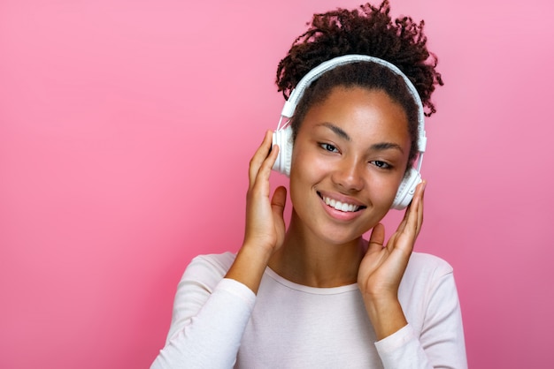 Retrato de una chica mulata bonita en auriculares escuchando música