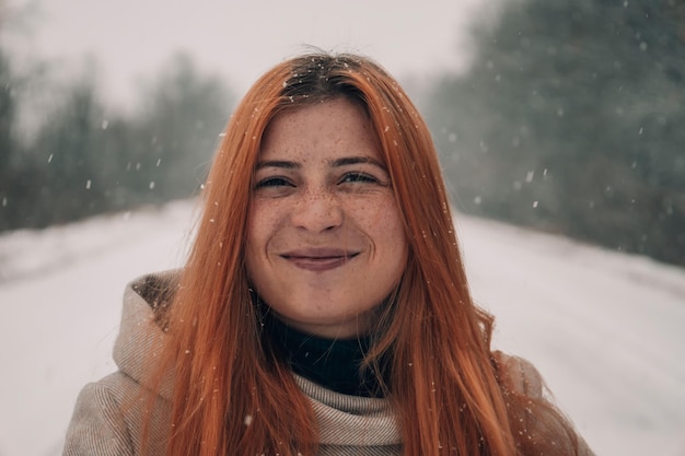 Retrato de una chica pelirroja con pecas en la cara Con fondo de nieve borroso