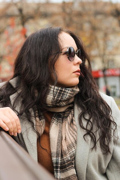 Retrato de chica rizada con estilo en abrigo y gafas