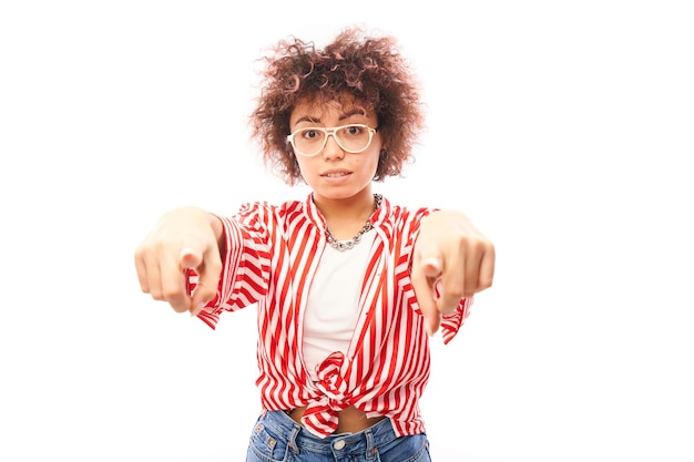 Retrato de una chica rizada positiva y amistosa te elige señalando con el dedo a la cámara aislada de fondo blanco