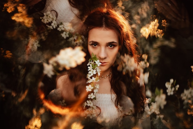 Retrato de una chica romántica en un jardín florido con elementos de fantasmagoría. El concepto de fantasía, cuentos de hadas.