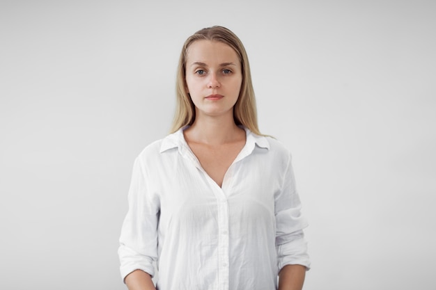 Retrato de chica rubia con camisa blanca sobre pared blanca,