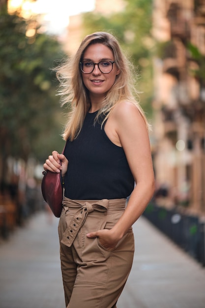 Retrato de una chica rubia con gafas posando para una sesión de fotos en una calle de la ciudad de Barcelona.